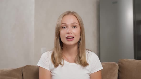 Pretty Woman Talking and Gesturing While Sitting on Sofa