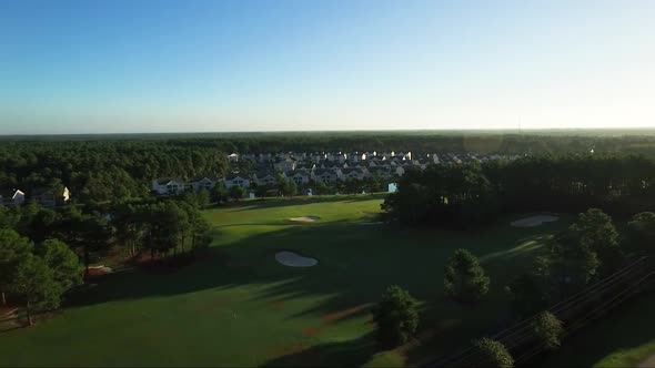 Drone flying away from houses located on golf course in early morning