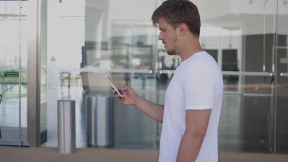 Side View of Young Man Using Smartphone During Stroll