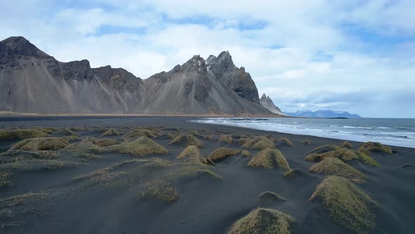 Stokksnes Vestrahorn Drone over black sand beach. in Iceland with jagged mountain peaks by the ocean