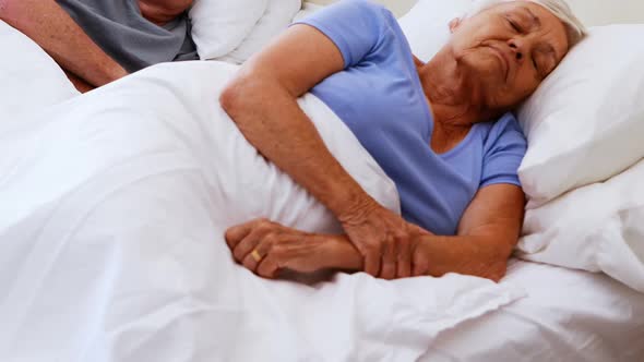 Senior couple sleeping on bed in bedroom