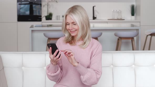 Happy Grey Haired Senior Woman Holding Smart Phone Looking at Cellphone Screen Playing Mobile Games