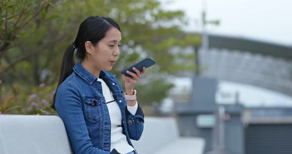 Woman Look at Mobile Phone and Sit on The Outdoor Bench