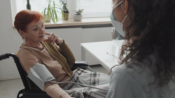 Senior Woman Talking to Nurse during Blood Pressure Monitoring