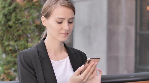 Young Businesswoman Using Smartphone Sitting Outdoor