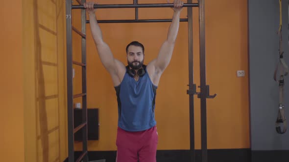 Workout of Handsome Young Middle Eastern Man in Gym. Strong Bearded Sportsman Hanging on Bars and