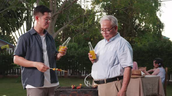 Happy Asian family having a barbecue-BBQ party together in the garden at home.