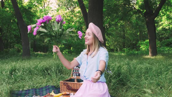 Happy Smiling Young Woman Having Fun with a Bouquet of Flowers Outdoors in Park on Picnic