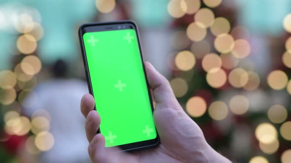 Hands Of Young Man Using Phone Against Illuminated Christmas Trees Outdoors