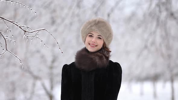 Beautiful redhead woman in hat in the winter park.