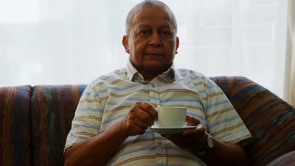 Portrait of senior man having coffee on sofa 4k