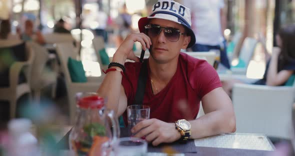 Man Talking By Phone Sitting in Outdoor Cafe