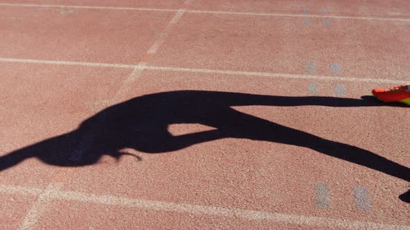 Low section of female athlete exercising on race track at sports venue 