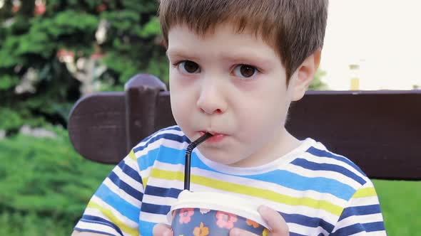 A Boy 4 Years Old Drinks Cocoa or a Milkshake From a Plastic Glass