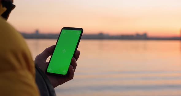 Man Using Green Screen in Smartphone Near River