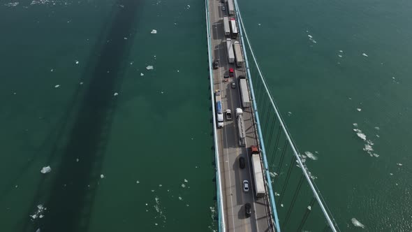 Trucks convoy trying to pass USA - Canada border over Ambassador bridge in Detroit, aerial view