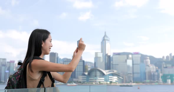 Young Woman taking photo with cellphone in Hong Kong Victoria harbor 