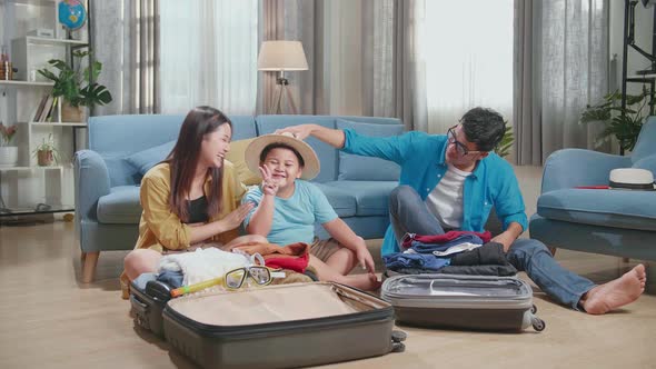 Happy Asian Family Packing Clothes In A Suitcase For A New Journey. Luggage For Travel Holidays