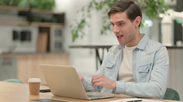 Successful Creative Young Man Celebrating on Laptop at Work