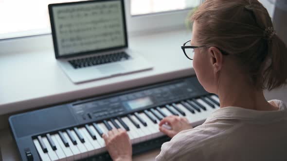 Back Shot of a Young Woman Playing on a Piano Keyboard