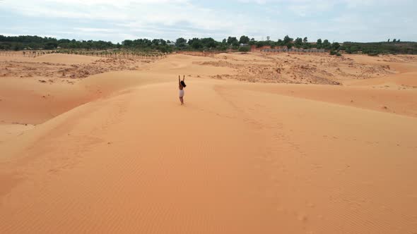 excited woman raising arms on top of desert sand dunes in Mui Ne Vietnam, aerial