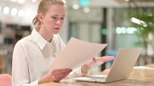 Beautiful Young Businesswoman Working on Laptop and Paperwork