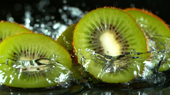 Super Slow Motion Shot of Falling And Splashing Kiwi Slice Isolated on Black Background at 1000Fps