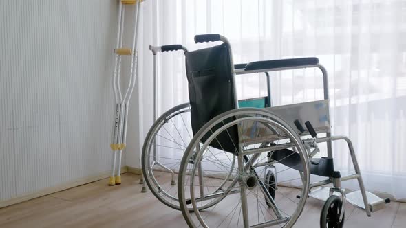 Empty modern wheelchair and walking stick or canes in hospital room.