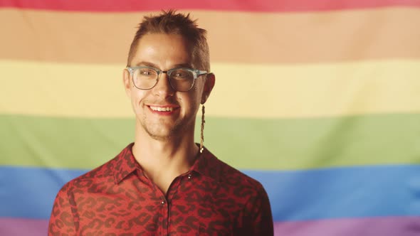 Joyous Gay Man with Makeup Posing against Pride Flag