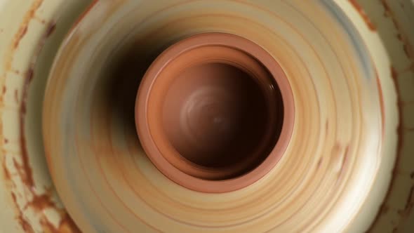 A clay pot rotates on a potter's wheel, top view. Ready-made clay pot