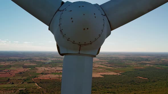 Close up aerial rising shot of stopped wind turbine, sunshine with light streaks in background