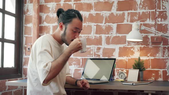 Asian man designer working home using laptop in living room at home.