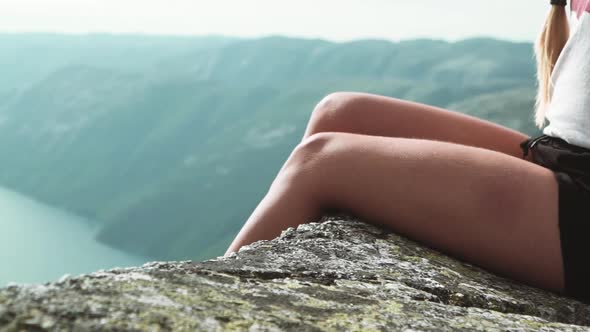 Halfbody Shot of a Female Hiker Sitting at the Edge of a Cliff at Kjeragbolten