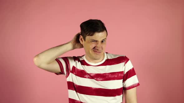 The Man Scratches His Head Trying To Remember Something. Male Thinks on a Pink Background