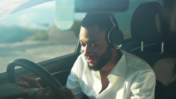 Joyful Handsome Young African American Gay Man Listening to Music in Headphone Sitting in Right Hand