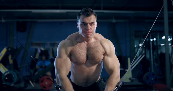 Bodybuilder Doing Exercise on the Simulator in the Gym