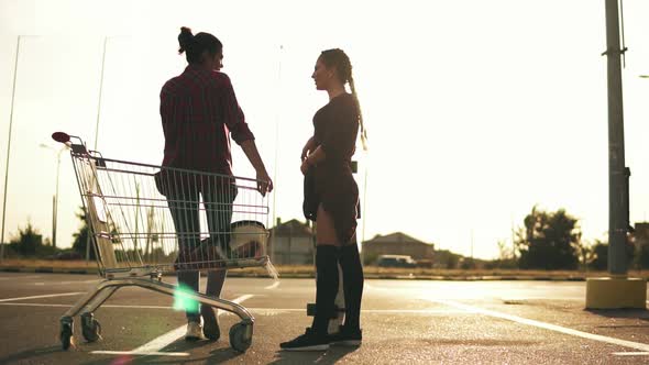 Young Attractive Girl in Long Socks is Holding a Skateboard and Talking to Her Girlfriend That is