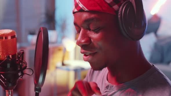 Close Up of Black Man Rapping in front of Microphone in Home Recording Studio