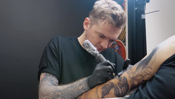 A Tattoo Artist with a Tattooed Arm Makes a Full Arm Tattoo to His Client