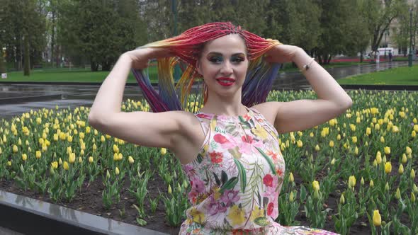 A Girl with Bright Makeup and African Rainbow Braids is Enjoying the Arrival of Spring in Blooming