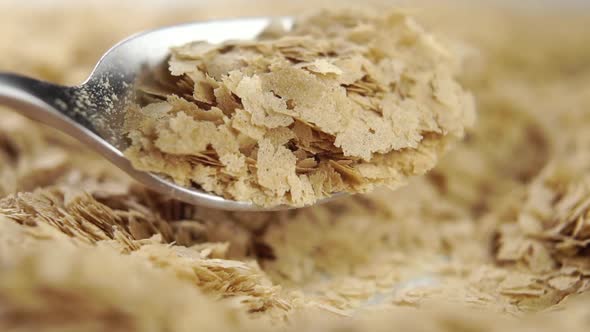 Brewer's yeast flakes. Falling from a spoon in slow motion. Natural supplement. Macro