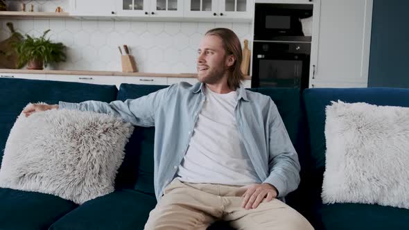 An Attractive Hipster is Relaxing at Home on His Couch in a Beautiful Minimalistic Interior Smiling
