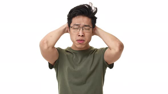 Portrait of Anxious Asian Man 20s Wearing Glasses Grabbing Head in Confusion While Expressing Stress