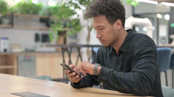 African American Man Celebrating While Using Smartphone