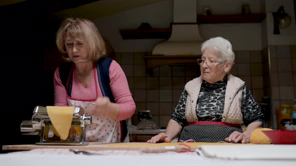 Aged women cooking tortellini together in kitchen