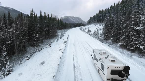 Aerial footage of traveling trailer through the winter forest in the mountains in Alberta, Canada