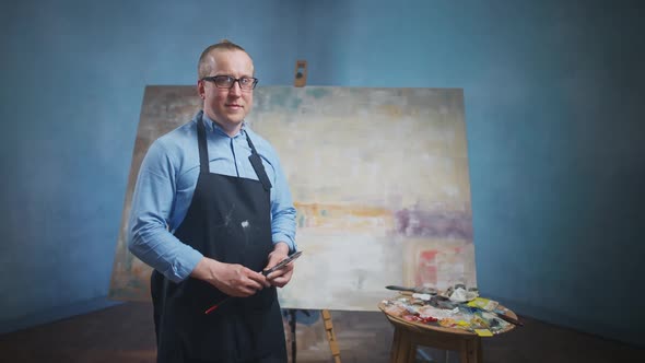 Slow Motion Portrait of an Adult Man Artist Standing Against the Background of a Large Canvas a Man