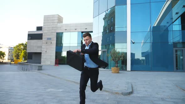 Young Businessman with Briefcase Runs and Looks at His Watch