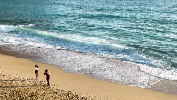 Girls take pictures on the beach Aerial view 4 K