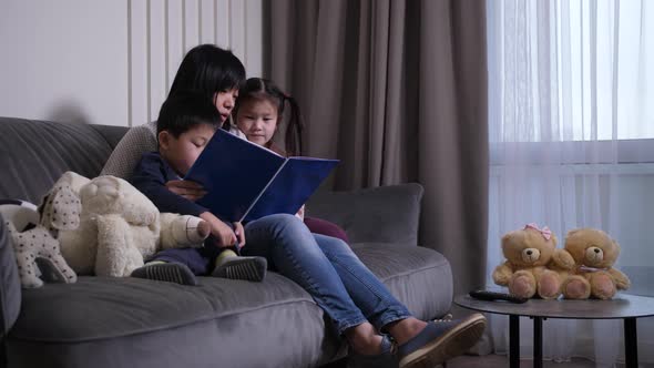 Caring Asian Mother Reading Book To Little Kids